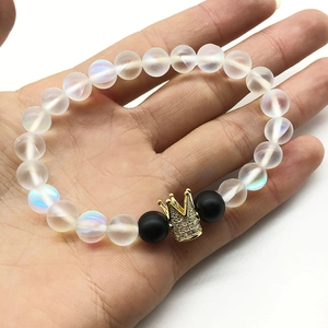 Bracelet en pierre de lune avec couronne dorée et strass tenu dans la main