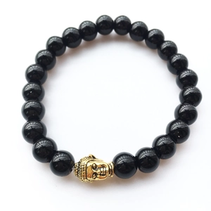 Gros plan des perles en agate noire et d'une tête de Bouddha dorée sur le bracelet