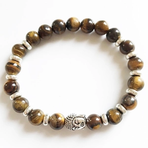 Macro shot of natural tiger eye beads with silver Buddha head charm on a beaded bracelet
