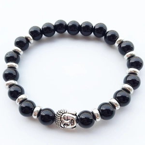 Macro shot of black beads and silver Buddha head charm on a spiritual beaded bracelet