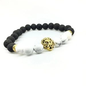 Détail d'un bracelet en pierre de lave noire, perles marbrées blanches et tête de lion