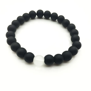 Primer plano de pulsera con cuentas negras mates de 8mm y una cuenta blanca translúcida