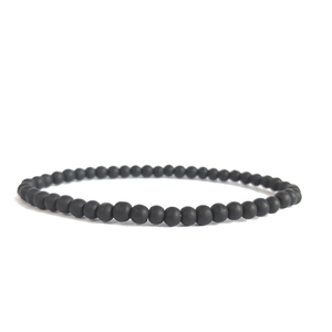 Macro detail of a 4mm matte black stone bead bracelet with a minimalist elastic cord design