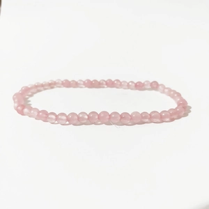 Macro view of 4mm rose quartz beads on a polished pink crystal energy stretch bracelet