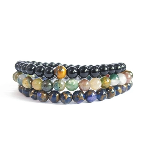 Close-up of stacked natural stone bracelets with tiger eye, onyx, and lapis beads