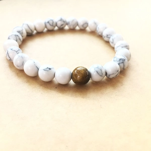 Detailed view of white turquoise beads with a brown tiger eye stone on elastic cord
