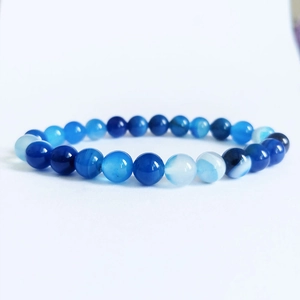 Détail macro du bracelet en perles avec texture naturelle d'agate rayée bleue et polie