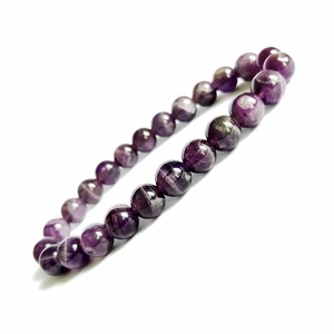 Dettaglio macro di perline tonde in ametista viola naturale su bracciale elastico
