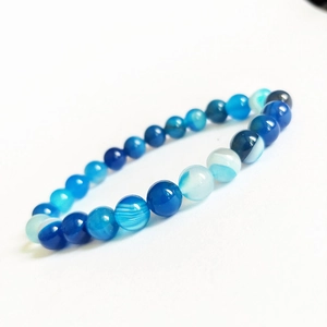 Détail de bracelet en perles d'agate bleue à rayures avec textures naturelles en dégradé