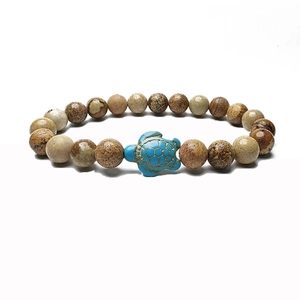 Macro detail of elastic beaded bracelet with brown marble stones and a blue sea turtle charm