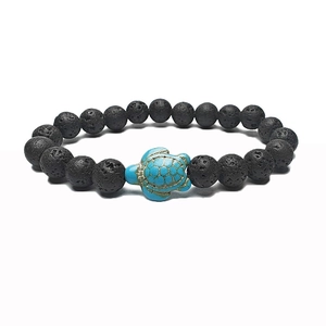 Macro detail of black volcanic lava beads and green turquoise turtle charm on a bracelet