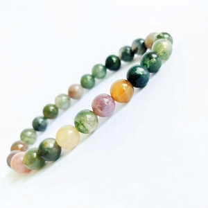 Macro shot of multi-color natural moss agate gemstone beads in a round stretch bracelet