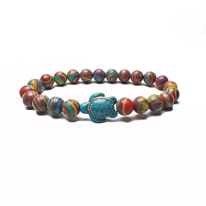 Detail of bohemian colorful striped beads with a turquoise turtle charm on a white background