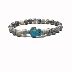 Close-up of beaded stretch bracelet featuring a turquoise turtle charm and marble beads