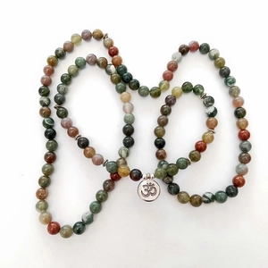Detailed macro view of natural Indian agate beads with a vintage silver Om symbol pendant