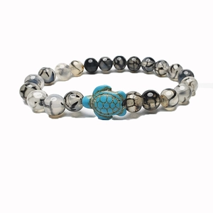 Macro detail of elastic beaded bracelet featuring a turquoise turtle and textured agate beads