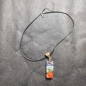 Macro-opname van 7 chakra stenen hanger met koperen spiraal en zwart wax koord