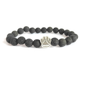 Macro detail of black lava stone beads and silver animal paw pendant on the bracelet
