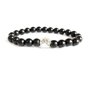 Detail of beaded bracelet with black matte beads and silver animal paw print charm