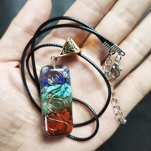 Detailweergave van de 7 chakra hars hanger met kristallen en koperen spiraalspoel