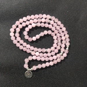 Roze kwartskristallen meerlaagse armband met zilveren lotus hanger op zwarte achtergrond
