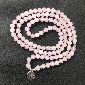 Roze natuursteen 108 kralen wikkelarmband met zilveren lotus hanger op zwarte achtergrond
