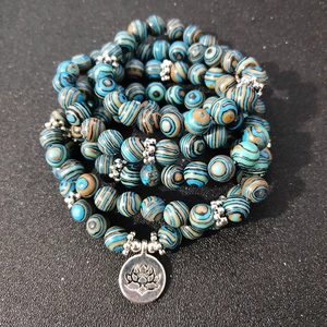 Blue malachite 108 beads yoga bracelet with silver lotus charm on black background