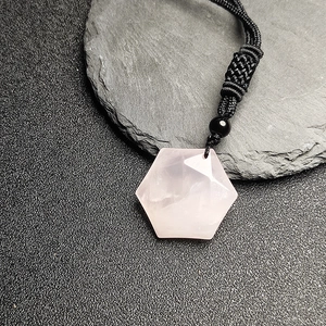 Dettaglio di un ciondolo esagonale in quarzo rosa con cordoncino nero intrecciato