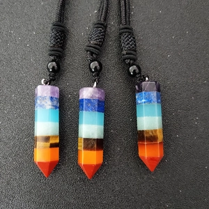 Detailansicht von drei hexagonalen Chakra-Heilstein-Anhängern mit schwarzen Kordeln