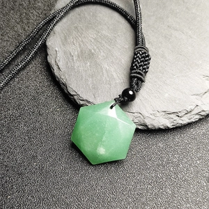 Macro del ciondolo esagonale in gemma verde con cordino nero intrecciato a mano