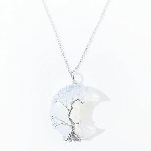 Detailed macro view of moon-shaped crystal pendant with wire wrapped tree of life design.