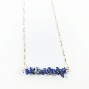 Detail of blue natural stone chips on a delicate gold chain necklace with minimalist style