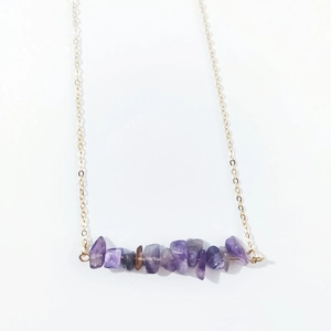 Close-up of irregular purple amethyst stone pendant on a delicate gold chain necklace