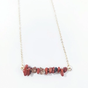 Close-up of red jasper natural stone chips on a minimalist gold link chain necklace