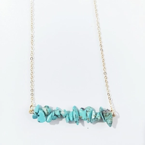 Macro shot of irregular turquoise stone beads on a delicate minimalist gold chain