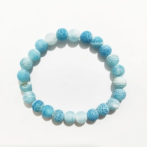 Close-up of 8mm dragon vein agate beads with blue and white cracked textures on elastic cord