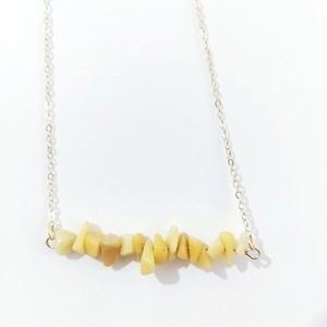 Macro view of natural yellow crystal stones on a delicate golden link chain necklace