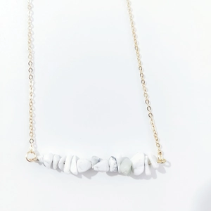 Detail of bohemian gold chain necklace with horizontal white turquoise stone pendant