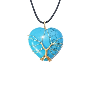 Macro detail of turquoise heart pendant with gold wire tree of life wrapping on black cord