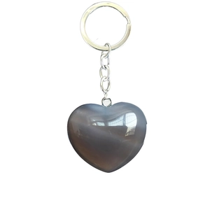 Macro detail of a heart-shaped grey natural stone keychain with silver metal ring