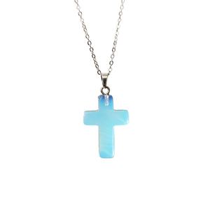 Gros plan d'un pendentif croix en cristal bleu clair avec une fine chaîne en métal argenté