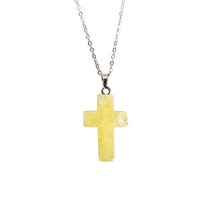 Détail d'un pendentif croix en pierre naturelle jaune sur une fine chaîne de collier argentée
