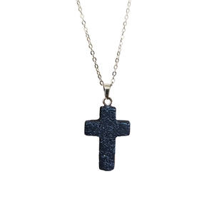 Détail macro du pendentif croix en pierre de lave naturelle et chaîne argentée