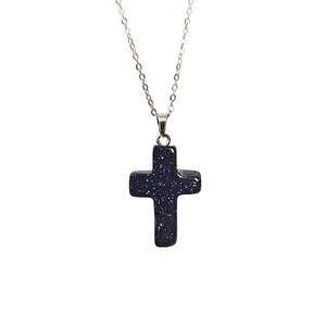 Détail macro du pendentif croix en grès bleu scintillant avec une fine chaîne argent