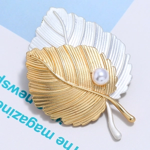 Détail d'une broche feuille bicolore or et argent mat ornée d'une perle d'imitation