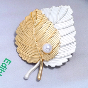 Détail de la broche feuille en bicolore or et argent avec une perle blanche d'imitation