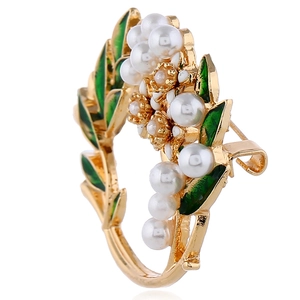 Detailaufnahme der goldenen Kranz-Brosche mit grünen Emaille-Blättern und Perlen