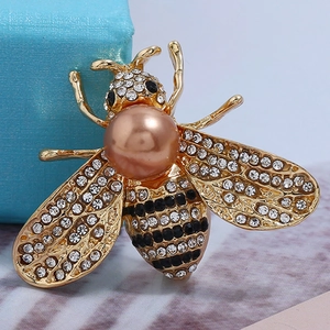 Detailed macro shot of honey bee brooch with metallic pearl and white rhinestones