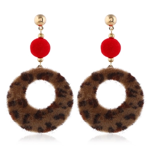 Detail of plush leopard print hoop earrings with golden stud and red velvet spheres