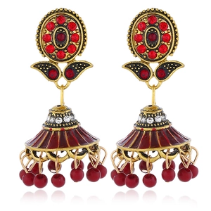 Detail of bohemian Jhumka earrings with red rhinestones and vintage gold finish